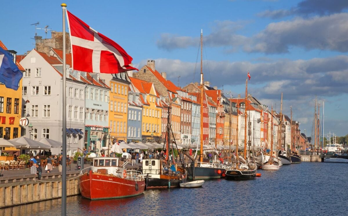 Photo shows a Danish flag flying in front of boats at Copenhagen Harbour