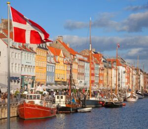 Photo shows a Danish flag flying in front of boats at Copenhagen Harbour