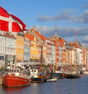 Photo shows a Danish flag flying in front of boats at Copenhagen Harbour