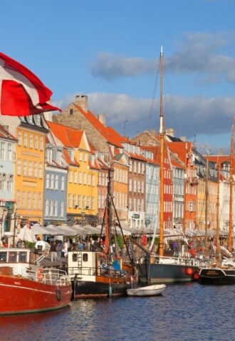Photo shows a Danish flag flying in front of boats at Copenhagen Harbour