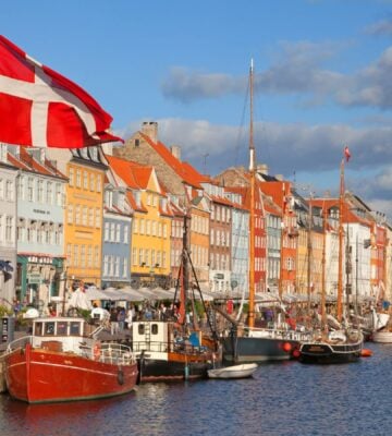 Photo shows a Danish flag flying in front of boats at Copenhagen Harbour