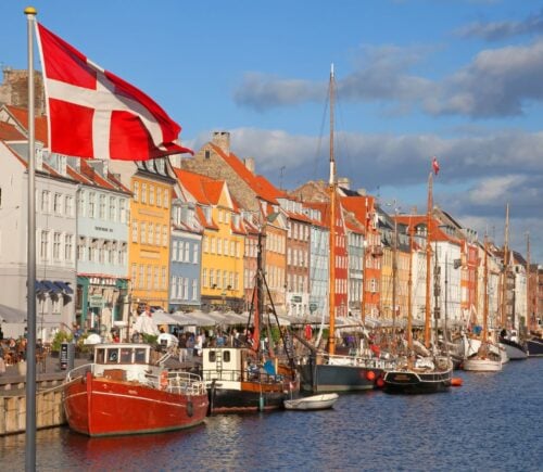 Photo shows a Danish flag flying in front of boats at Copenhagen Harbour