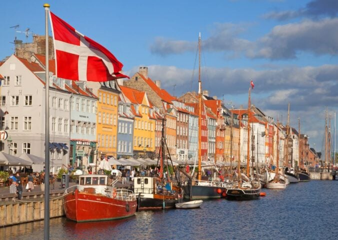 Photo shows a Danish flag flying in front of boats at Copenhagen Harbour