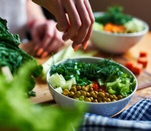 A close up of a hand making a healthy vegan salad with chickpeas and greens