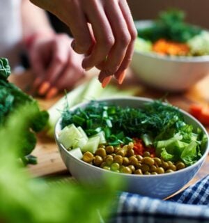 A close up of a hand making a healthy vegan salad with chickpeas and greens