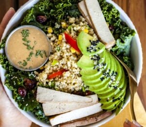 a bowl of kale salad with quinoa pilaf and creamy balsamic dressing