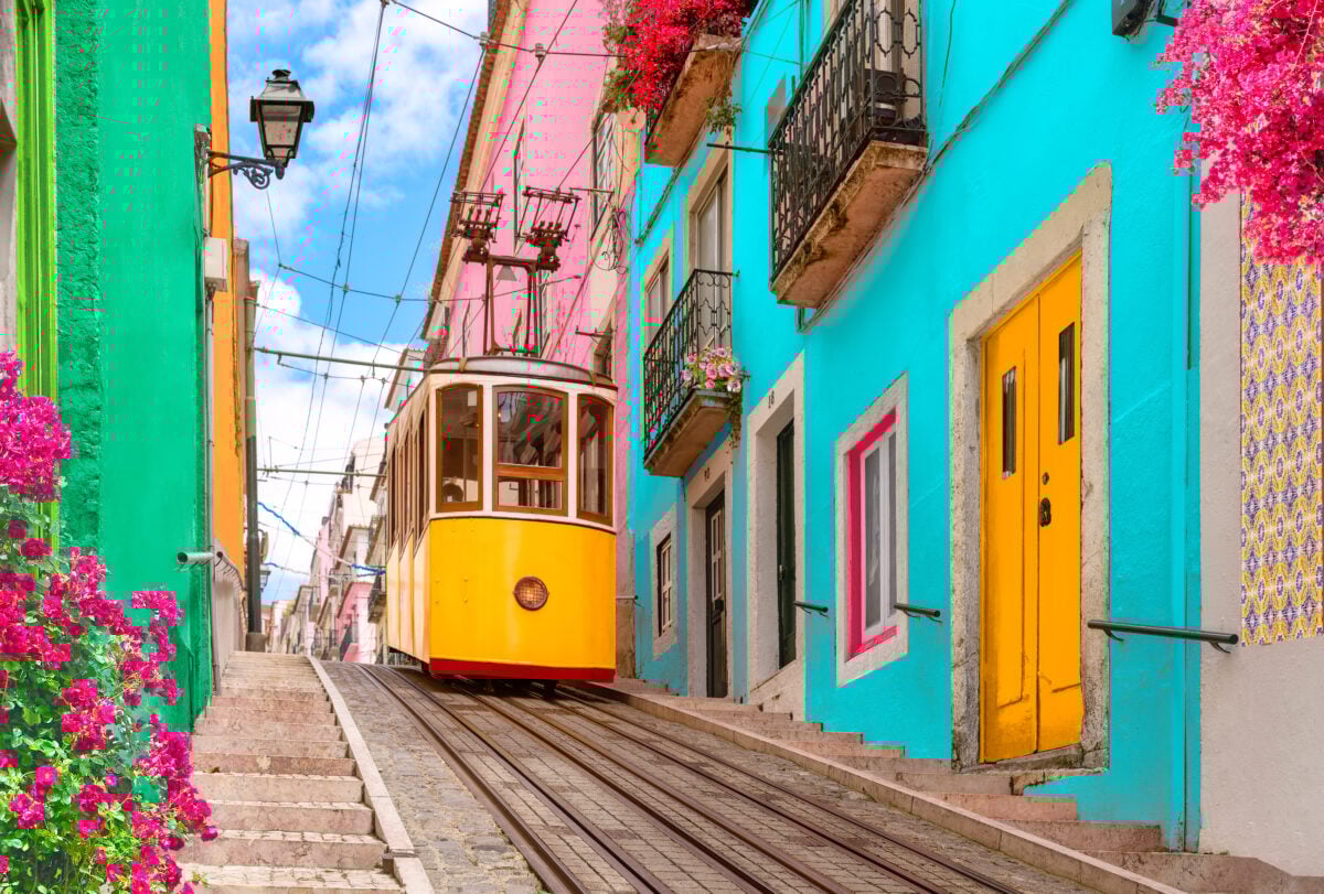 Colorful houses and doors on a Lisbon street with a yellow tram going down the road