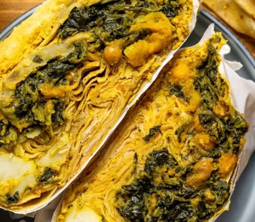 a loaded dhal puri roti with chana, aloo, and spinach