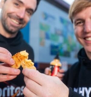 Photo shows two men in Doritos and NotCo branded sweatshirts holding Flamin' Hot flavored "NotChicken Nuggets" from the two brands