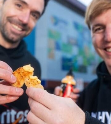 Photo shows two men in Doritos and NotCo branded sweatshirts holding Flamin' Hot flavored "NotChicken Nuggets" from the two brands