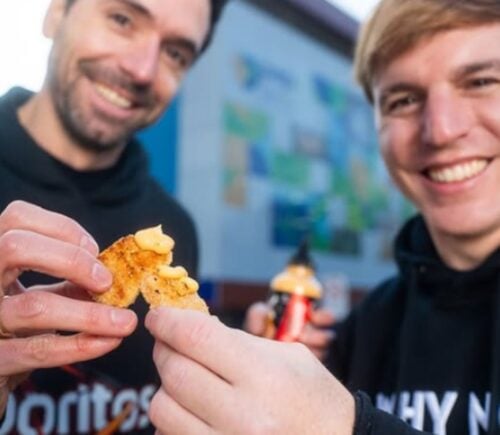Photo shows two men in Doritos and NotCo branded sweatshirts holding Flamin' Hot flavored "NotChicken Nuggets" from the two brands