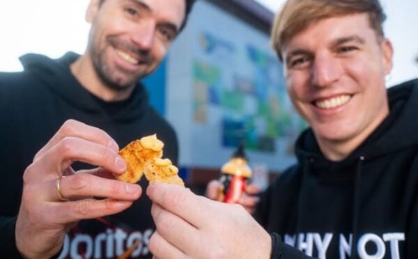 Photo shows two men in Doritos and NotCo branded sweatshirts holding Flamin' Hot flavored "NotChicken Nuggets" from the two brands