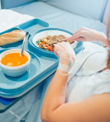 A woman eating plant-based food in a hospital bed