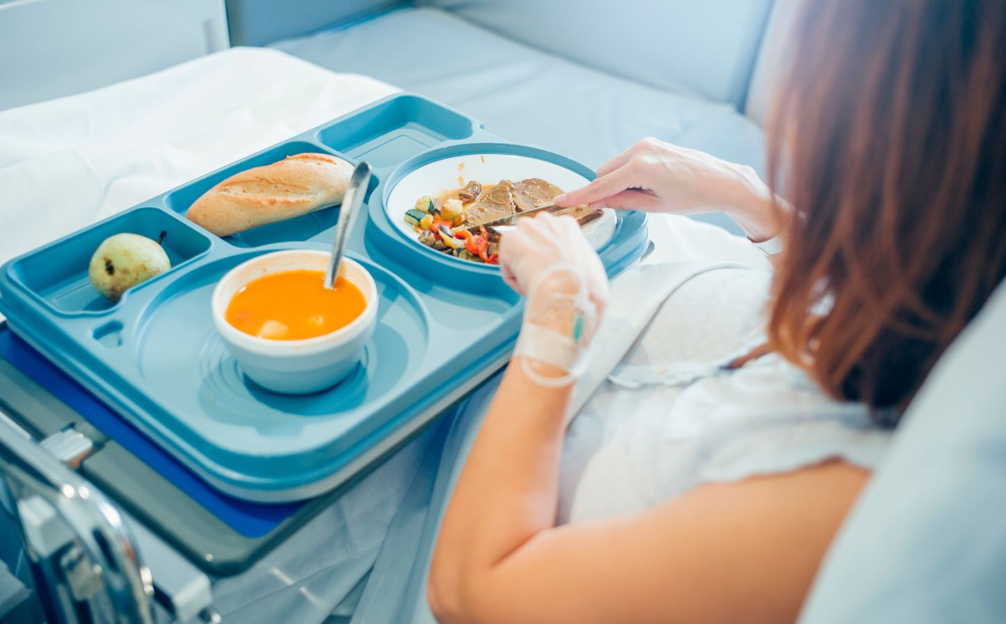 A woman eating plant-based food in a hospital bed
