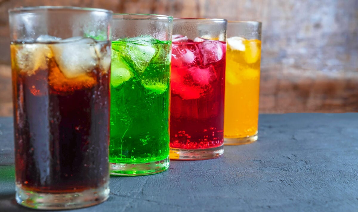 Photo shows a selection of colored soft drinks in glasses with ice