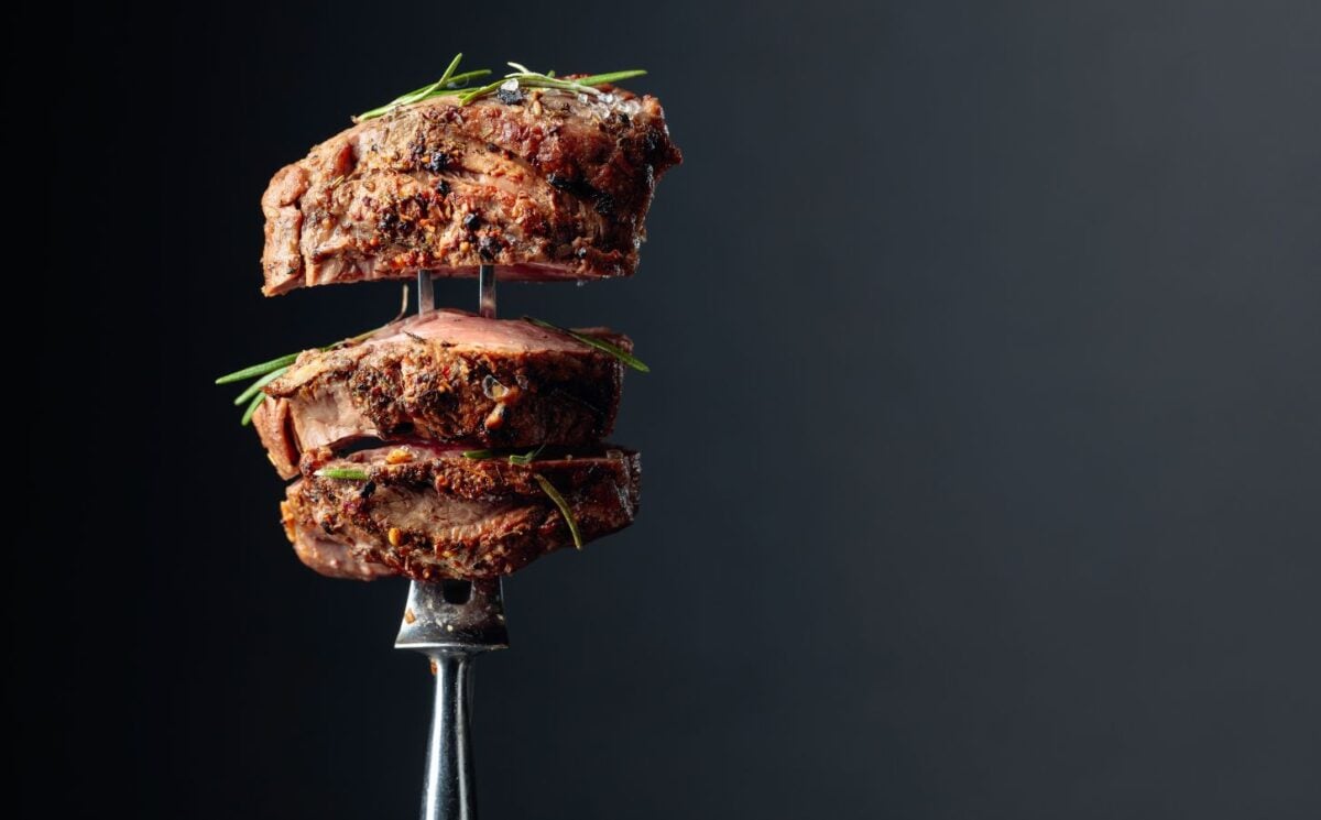 Photo shows a silver fork with several thick pieces of steak on it