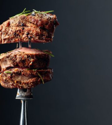 Photo shows a silver fork with several thick pieces of steak on it