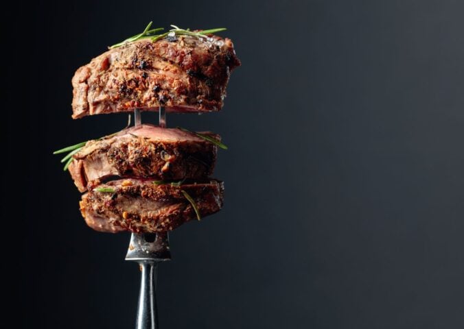 Photo shows a silver fork with several thick pieces of steak on it