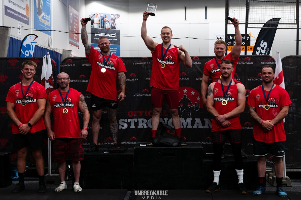 Photo shows vegan athlete Tom Butts on the podium alongside peers and competitors at the Official Strongman British Championships