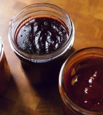 A shot of the three vegan bbq sauces, classic, blueberry, and peach habanero, all lined up in glass jam jars