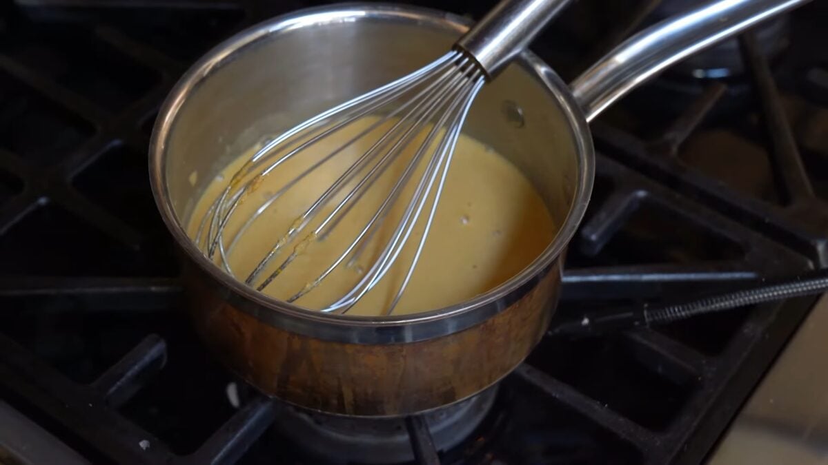 Schinner cooks mustard in a pot on her stovetop and whisks it up, in her video on how to make homemade vegan ketchup and mustard