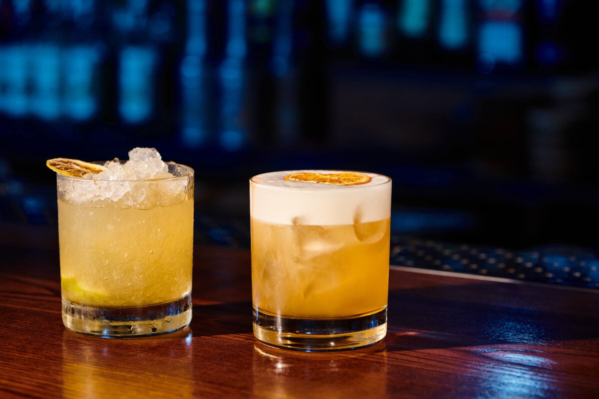 Two whiskey sour cocktails on a bar top