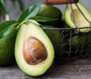 A basket of avocados, including a close-up of an avocado half