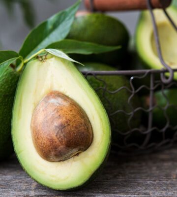 A basket of avocados, including a close-up of an avocado half