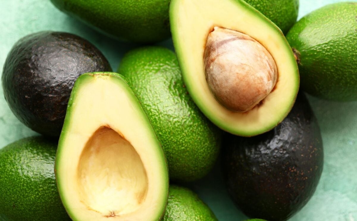 A selection of avocaods on a table, with a close-up of two avocado halves