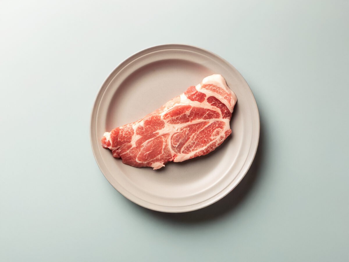 Photo shows a raw pork chop on a plate