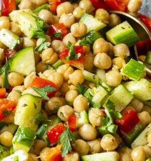 a herby chickpea salad with bell pepper, cucumber, garlic, lemon, and olive oil
