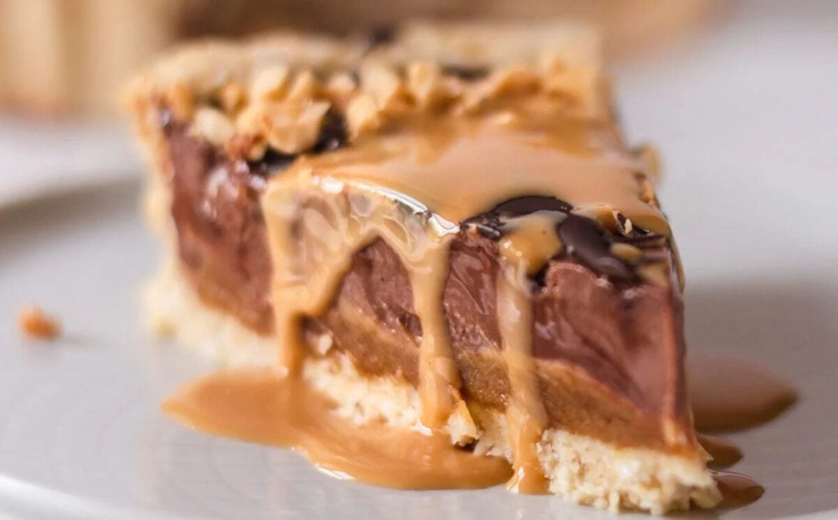no-bake snickers tart with a peanut butter base, peanut caramel, and chocolate ganache