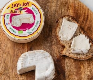Photo shows a wheel of "Albert," the vegan camembert from Jay & Joy, alongside the packaging and some spread on bread