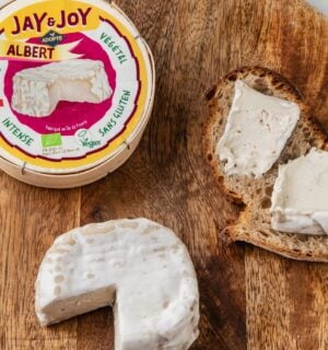 Photo shows a wheel of "Albert," the vegan camembert from Jay & Joy, alongside the packaging and some spread on bread