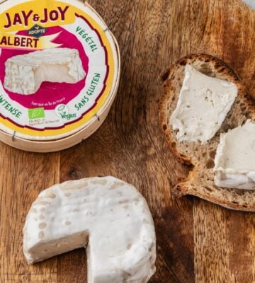 Photo shows a wheel of "Albert," the vegan camembert from Jay & Joy, alongside the packaging and some spread on bread