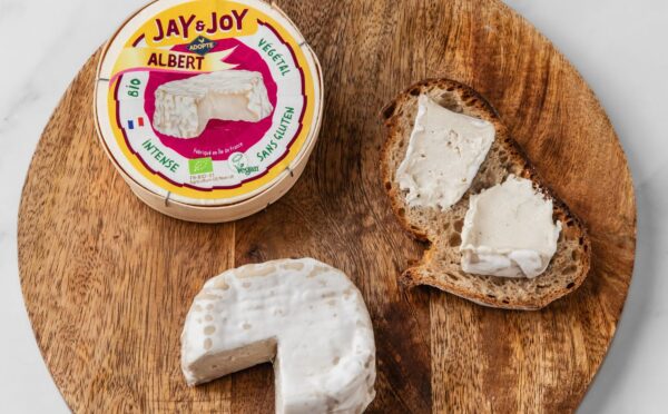 Photo shows a wheel of "Albert," the vegan camembert from Jay & Joy, alongside the packaging and some spread on bread