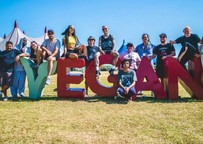 Vegan Camp Out attendees at the festival posting against some large letters reading "Vegan"