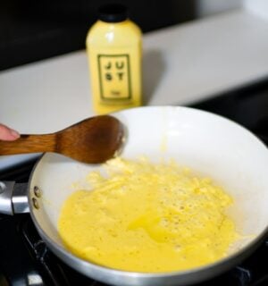 Photo shows someone cooking a pan of Eat Just's vegan egg product, "Just Egg," with the packaging visible in the background