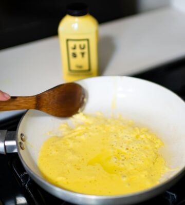Photo shows someone cooking a pan of Eat Just's vegan egg product, "Just Egg," with the packaging visible in the background