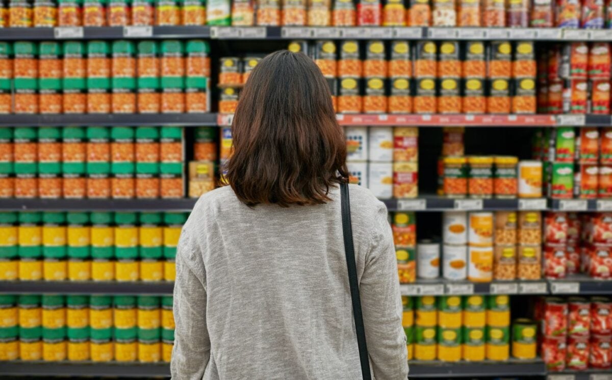 A woman looking at tins of beans at a supermarket