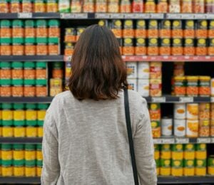A woman looking at tins of beans at a supermarket