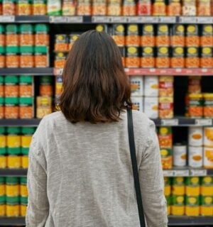 A woman looking at tins of beans at a supermarket