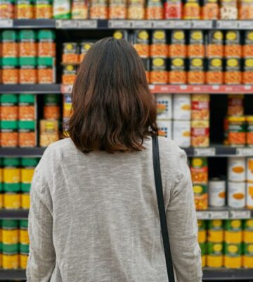 A woman looking at tins of beans at a supermarket