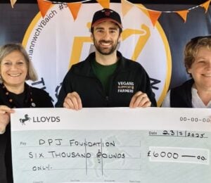 Photo shows people from Vegans Support the Farmers and the DPJ Foundation holding a cheque for the final amount at the Royal Welsh Show