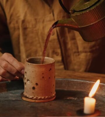Former chef Gaz Oakley pours tea into a clay mug while shooting his video about Herbal teas for energy, immunity, sleep, and love
