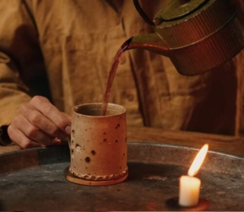 Former chef Gaz Oakley pours tea into a clay mug while shooting his video about Herbal teas for energy, immunity, sleep, and love