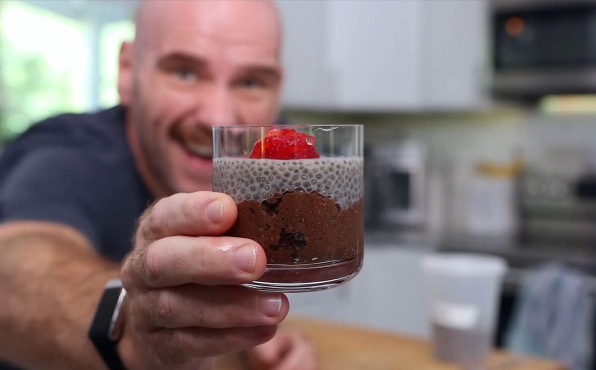 Mark Thompson stands in his kitchen holding a glass dessert cup of chia pudding in his video 'I Ate Chia Seeds Every Day for a Month.'