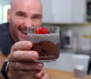Mark Thompson stands in his kitchen holding a glass dessert cup of chia pudding in his video 'I Ate Chia Seeds Every Day for a Month.'