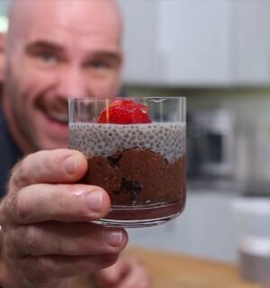 Mark Thompson stands in his kitchen holding a glass dessert cup of chia pudding in his video 'I Ate Chia Seeds Every Day for a Month.'