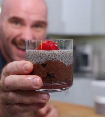 Mark Thompson stands in his kitchen holding a glass dessert cup of chia pudding in his video 'I Ate Chia Seeds Every Day for a Month.'